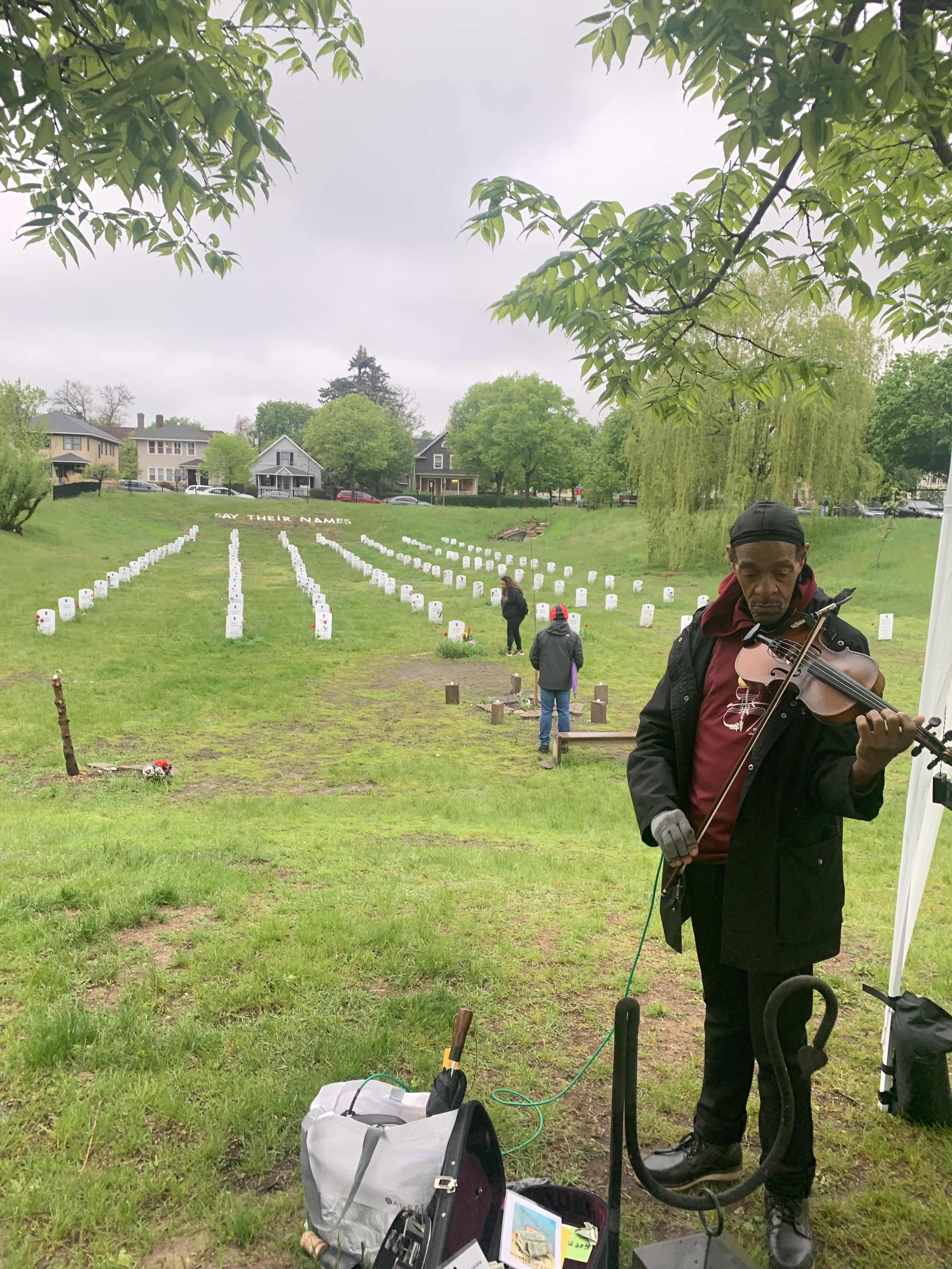 Man playing a violin in front of a cemetary.