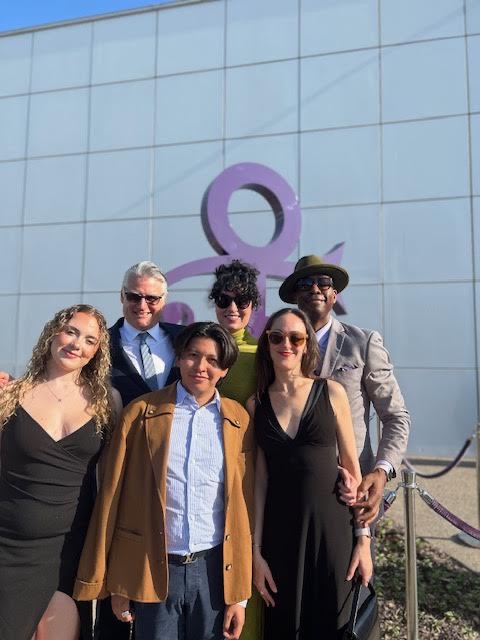 Six people pose in front of Prince's house: Paisley Park.