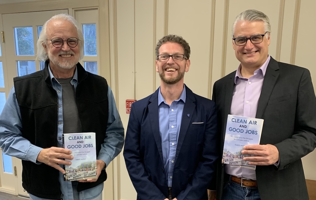 Three men stand side by side, two are holding up copies of "Clean Air and Good Jobs."
