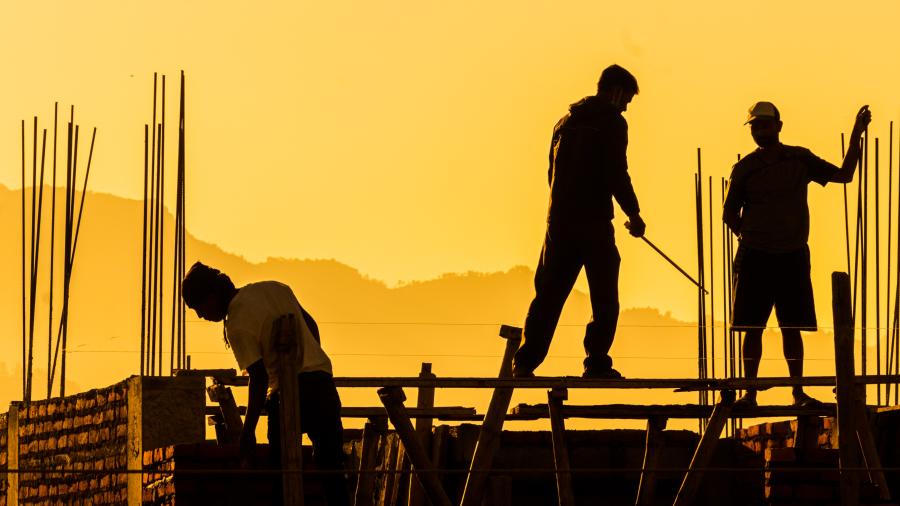 three builders against a yellow sky