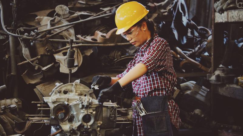 Woman working in a factory on a car engine