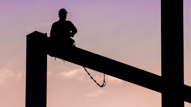Guy standing on roof beams against a purple sky
