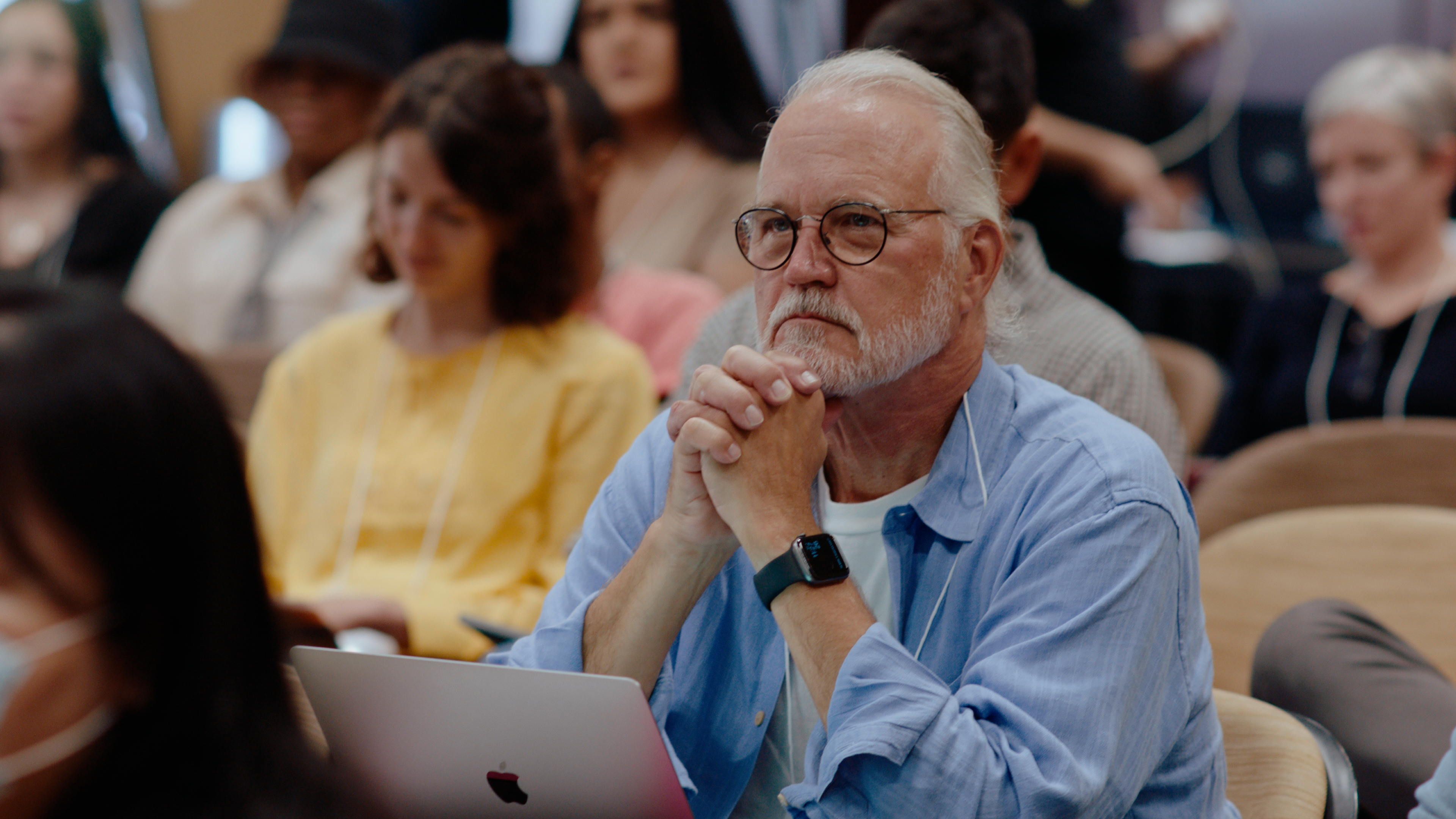 Craig Calhoun sits, listening with his hands beneath his chin.