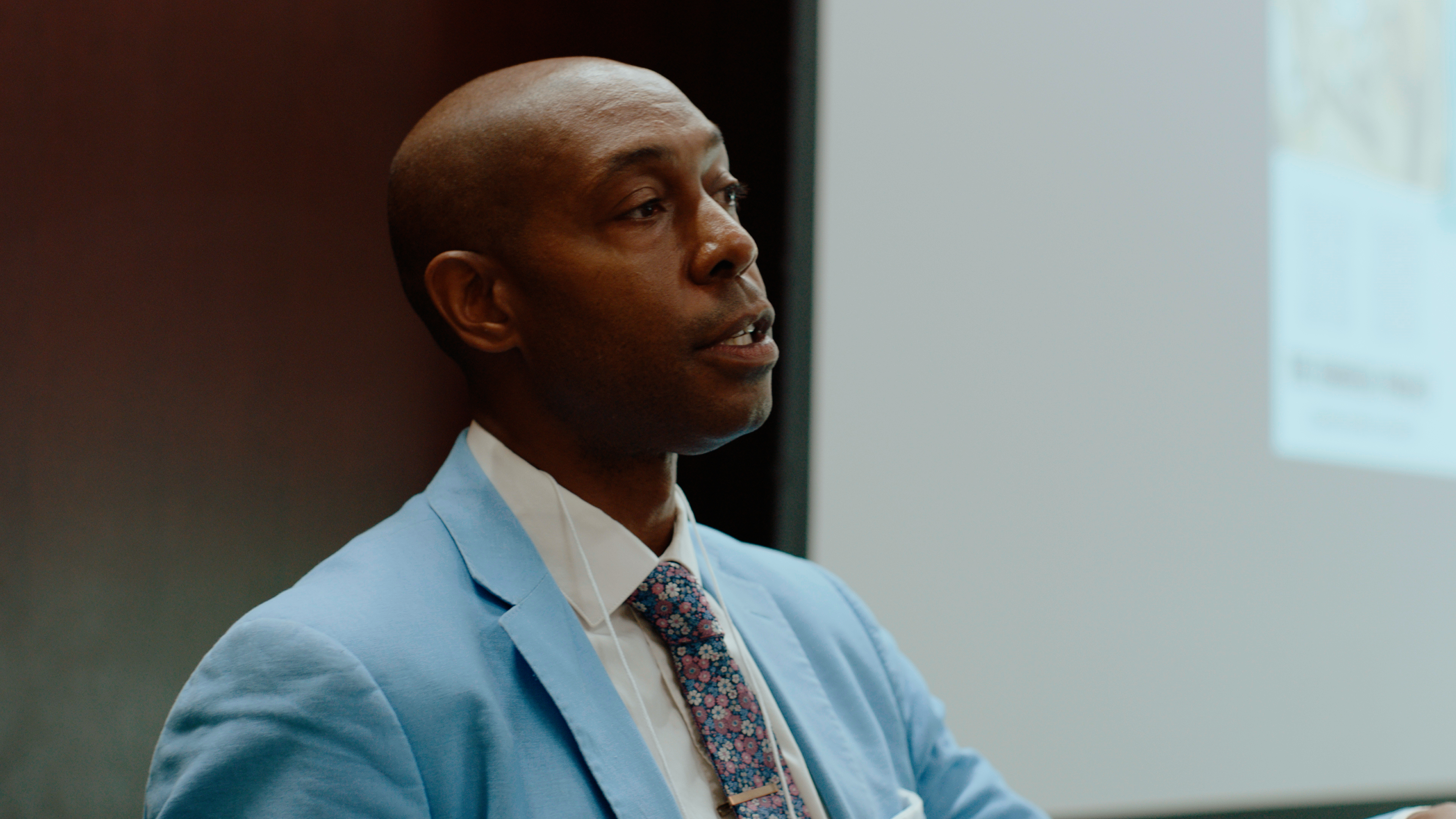 Man in a blue suit addresses the crowd.