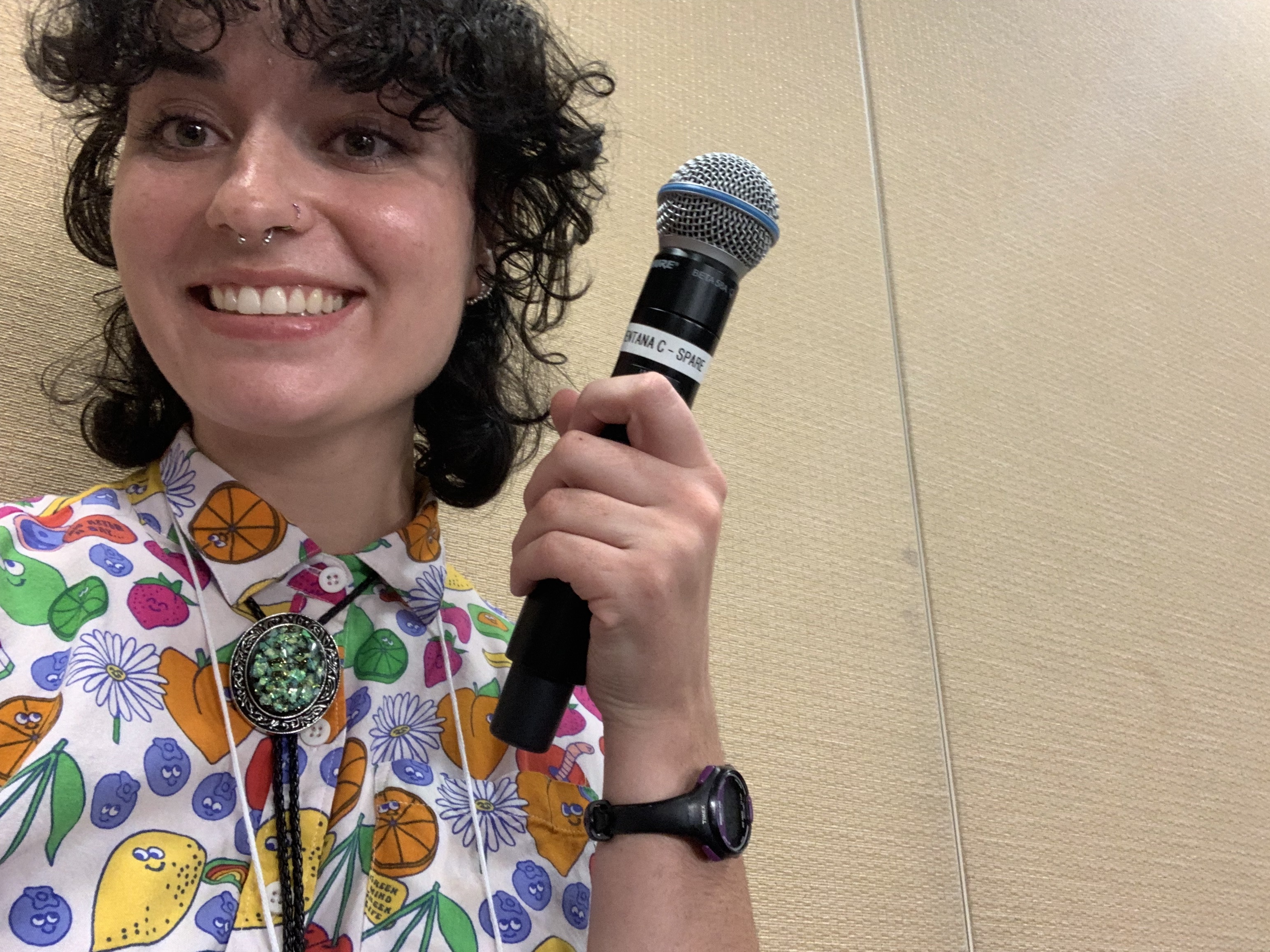 Woman holding a mic up and smiling.