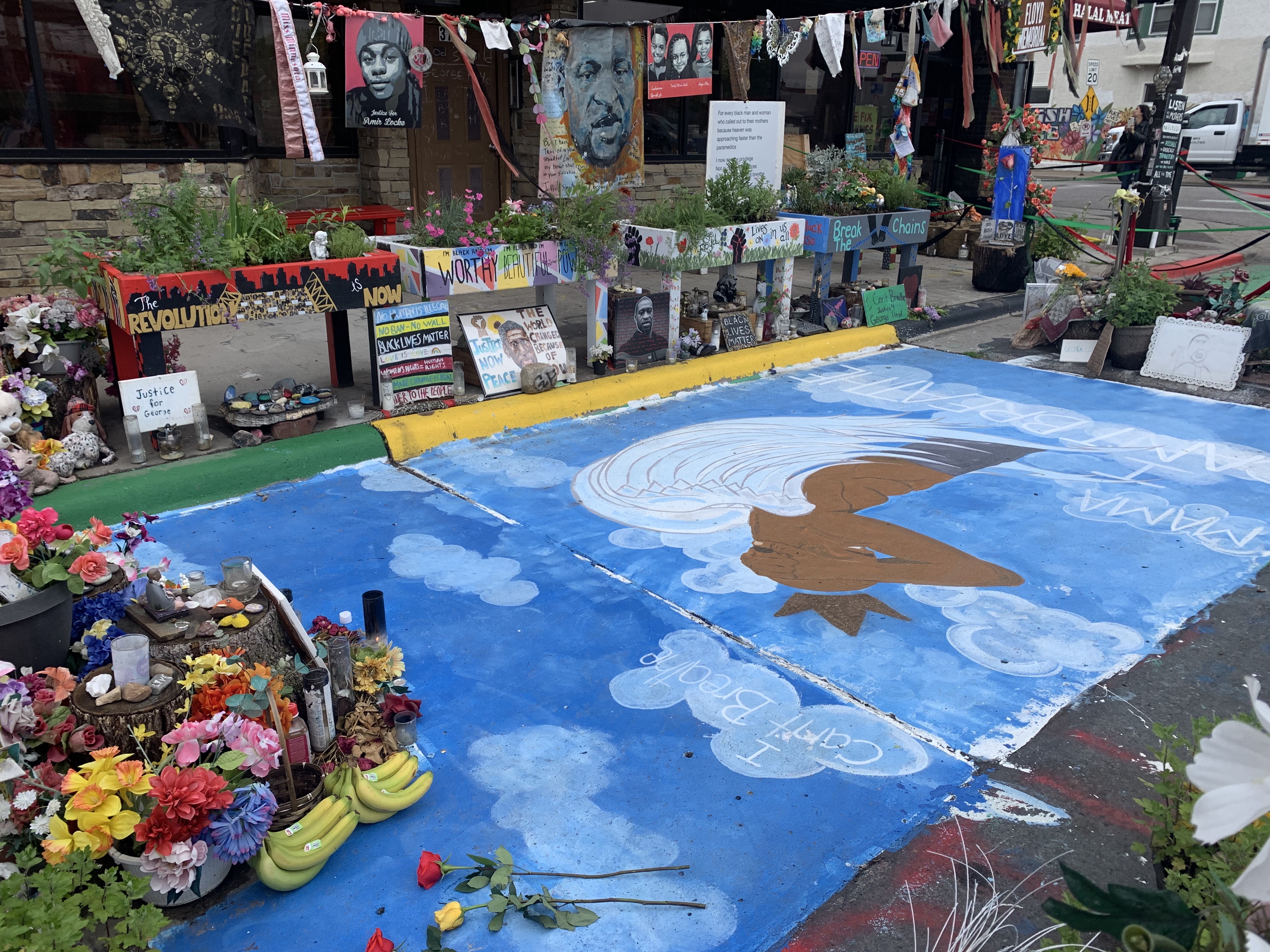painting on the street of a portrait in front of a blue sky.