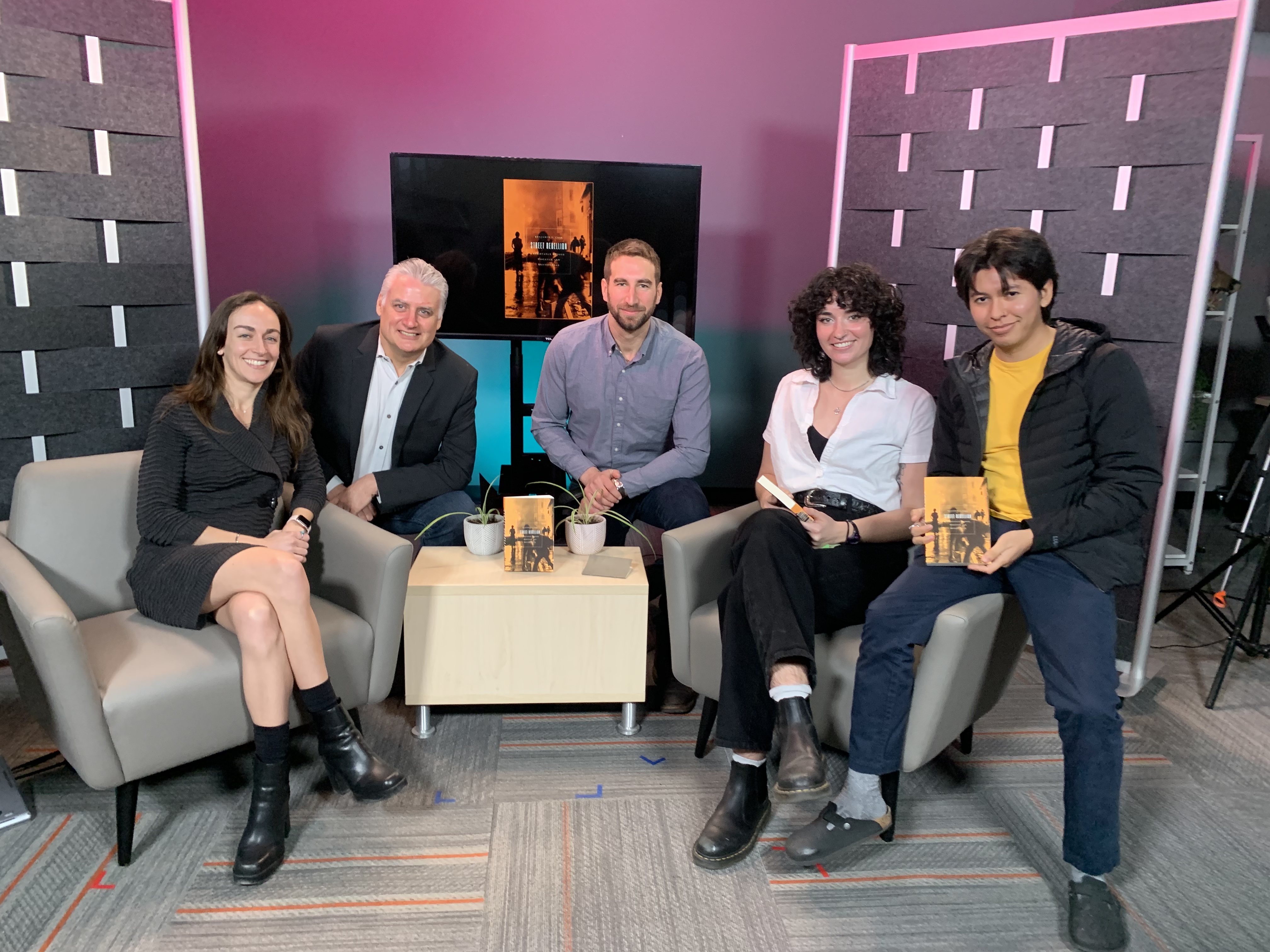 Five staff members sit on a film set.