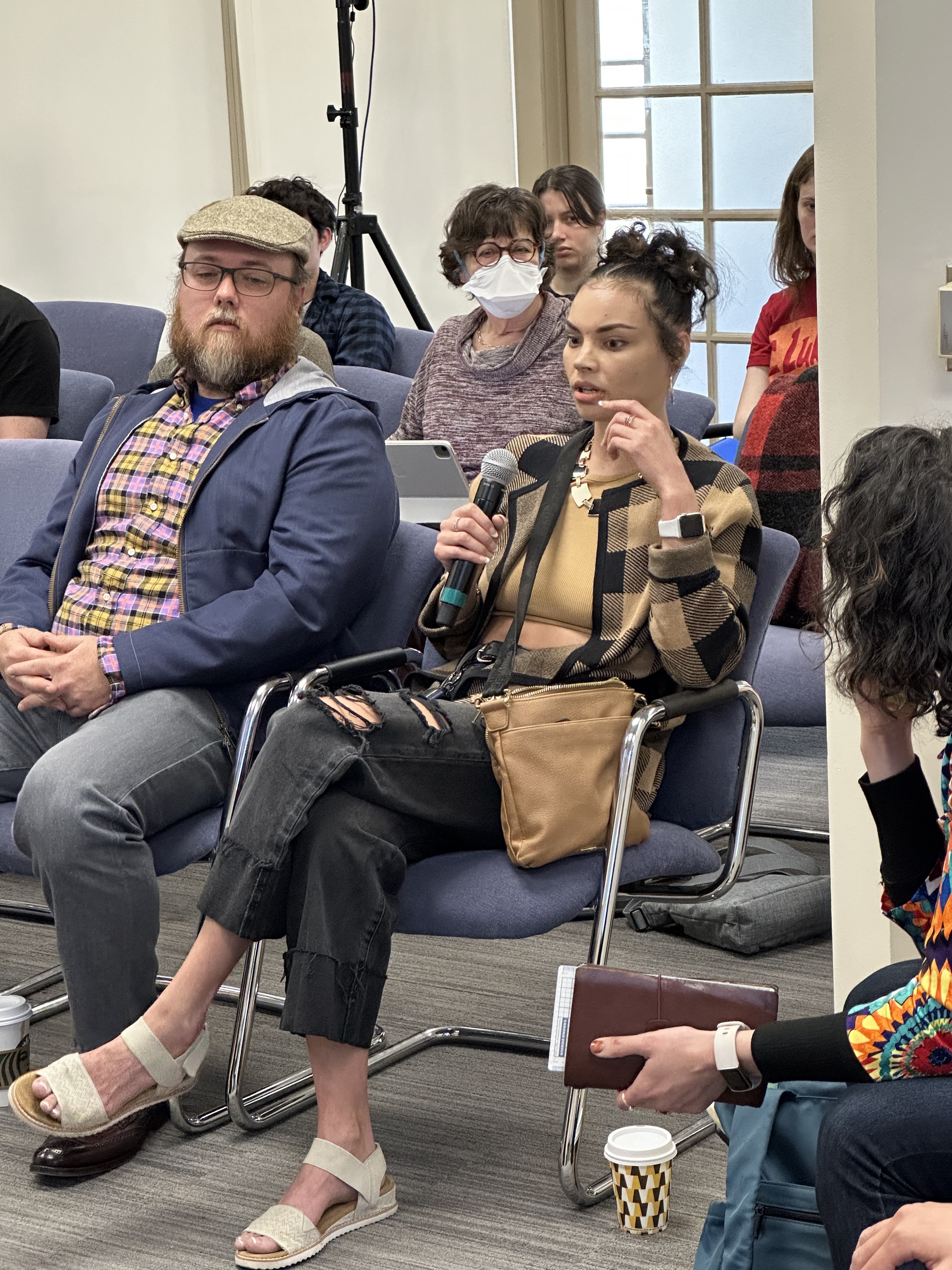 Woman, seated, speaks into a microphone.