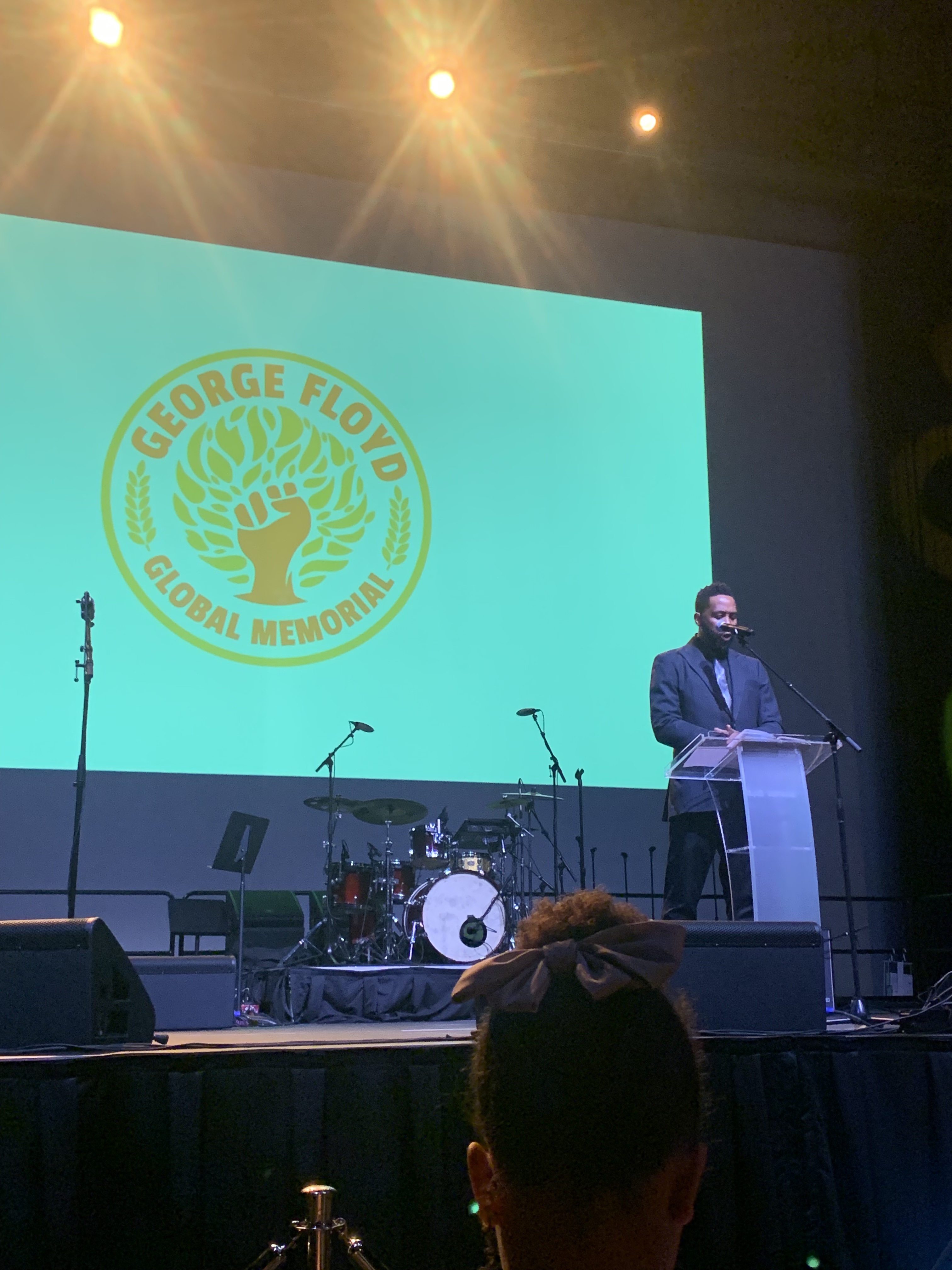 A man speaks at a podium in front of a large GFGM logo.