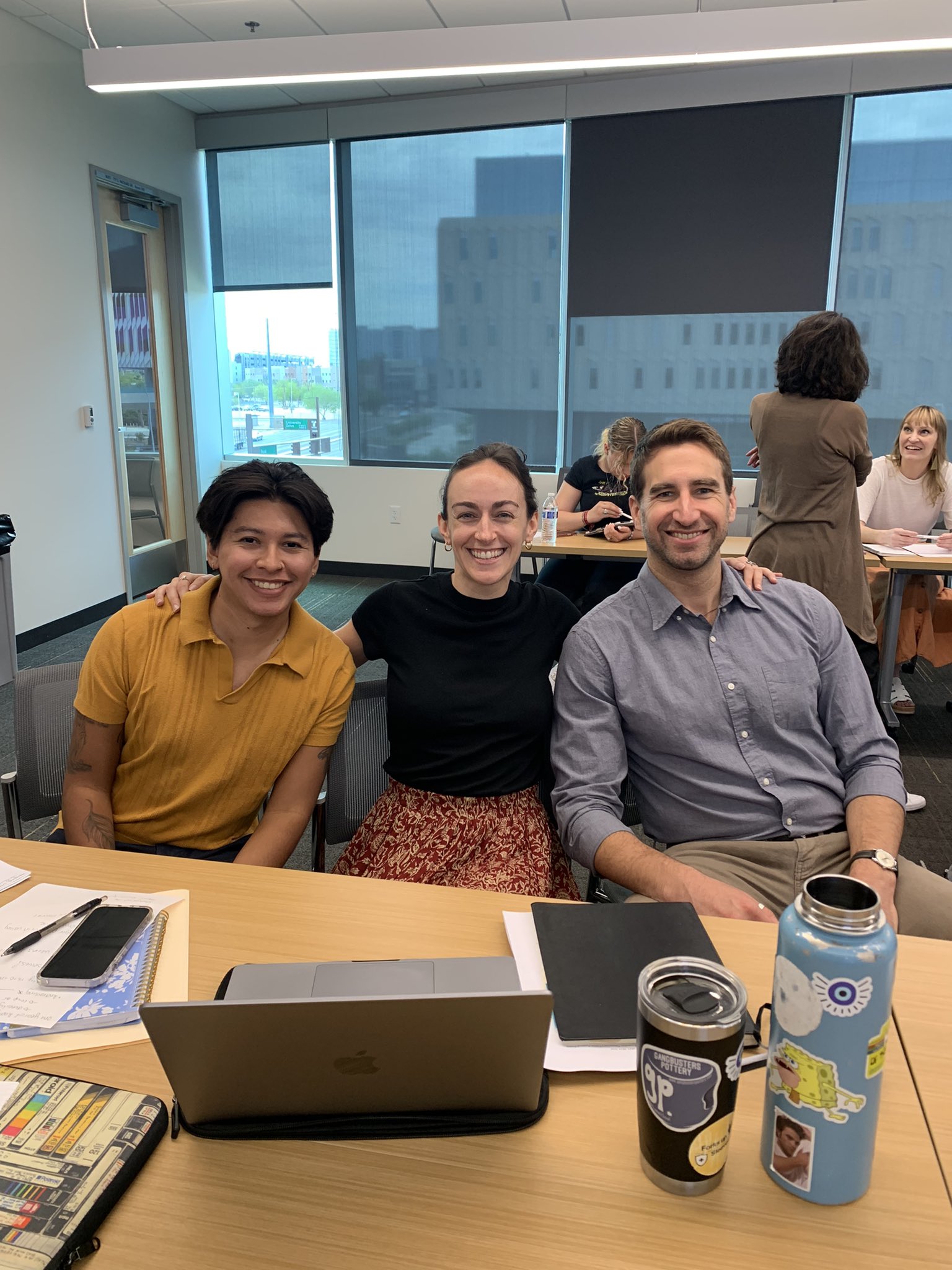 Three people, seated, smiling for a photo.