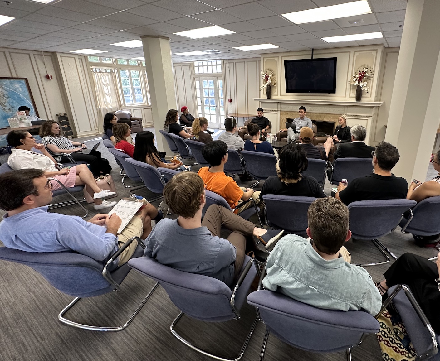 A crowd of seated people facing seated speakers at the front of the room.